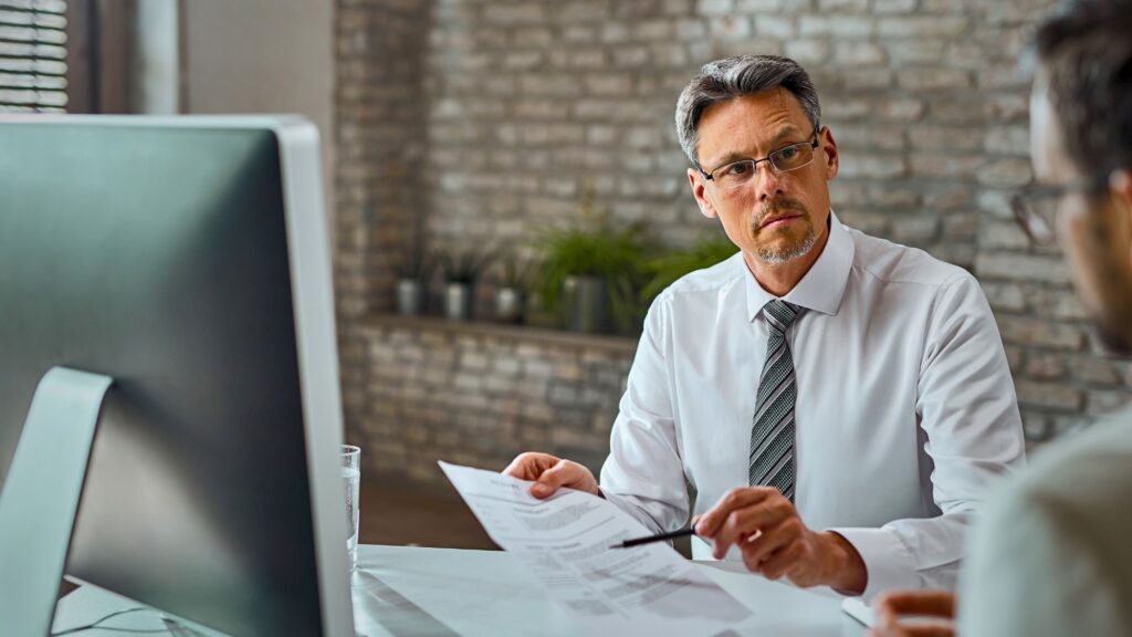 A tax accountant in a white shirt and tie engaged in conversation with a client