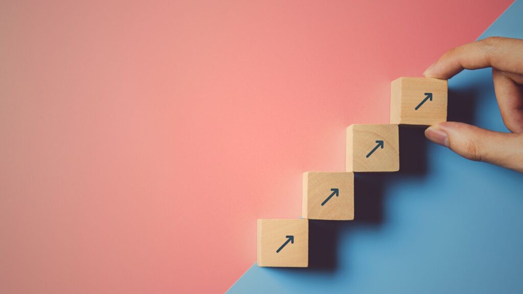 Hand holding wooden blocks with arrows pointing up, symbolizing data management and innovation