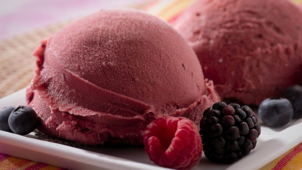 Two scoops of gelato ice cream topped with fresh berries and raspberries made with taylor ice cream machines